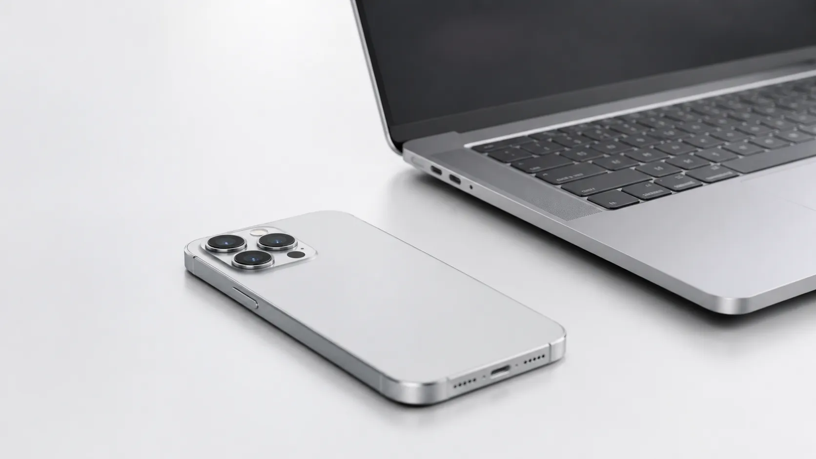 iPhone and MacBook on white desk illustrating methods to recover iPhone data